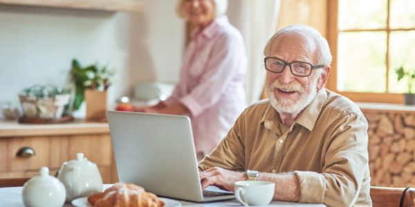 Smiling elderly spouses staying at the kitchen at their home